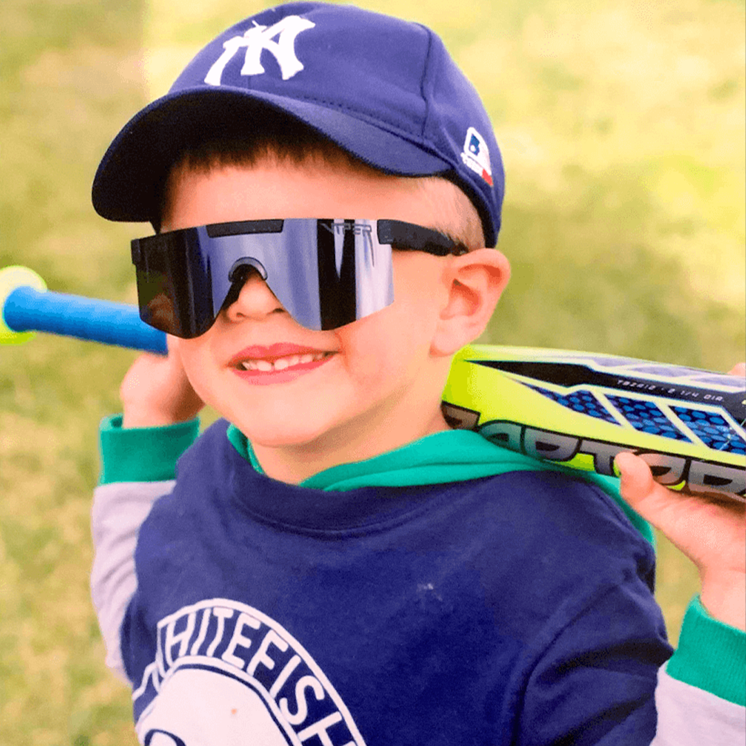 / Mirror | Kid holding a baseball bat in The Blacking Out XS from Pit Viper Sunglasses