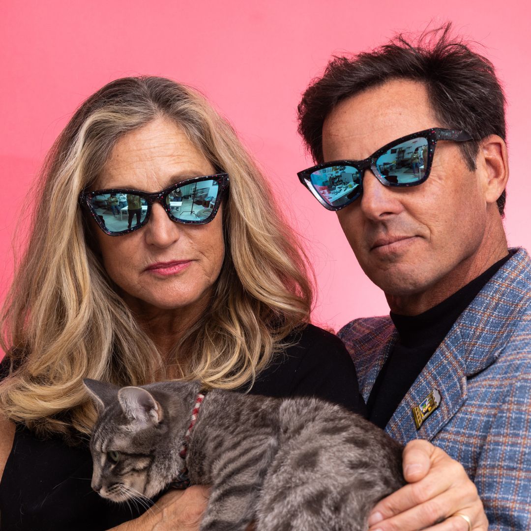 / Blue | A woman and a man wear The Midnight Clawdia with a blue lens from Pit Viper while holding a cat
